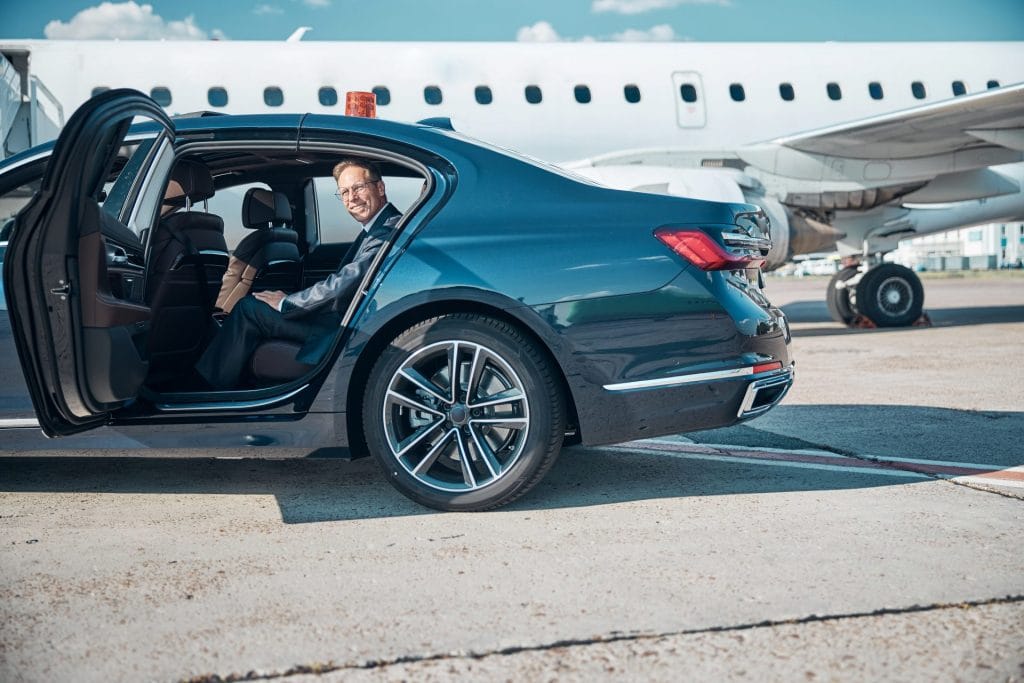 Smiling mature businessman in car near plane